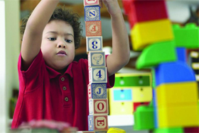 photo of boy building block tower