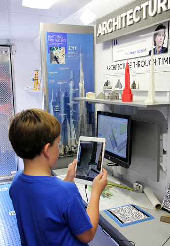 A fifth-grader uses an augmented reality app on an iPad at the architecture station inside the STEAM Express.